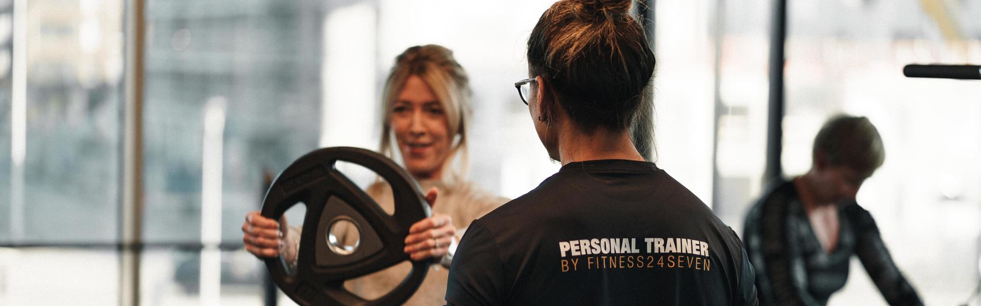 Personal trainer and female client doing front rise.