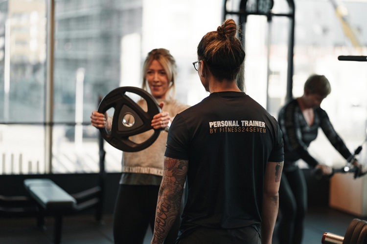 Personal trainer and female client doing front rise.