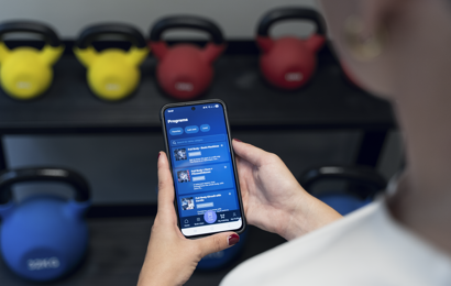 Medlem håller i mobil med Fitness24seven träningsprogram i appen
